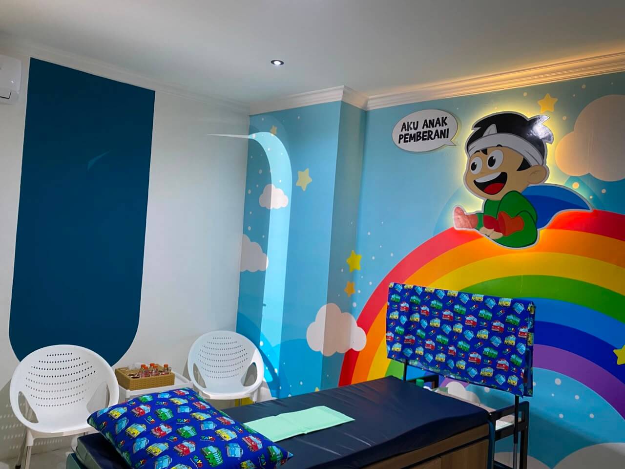 Ruang periksa anak dengan dekorasi pelangi dan karakter kartun yang ramah anak