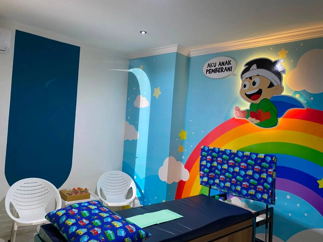Ruang periksa anak dengan dekorasi pelangi dan karakter kartun yang ramah anak