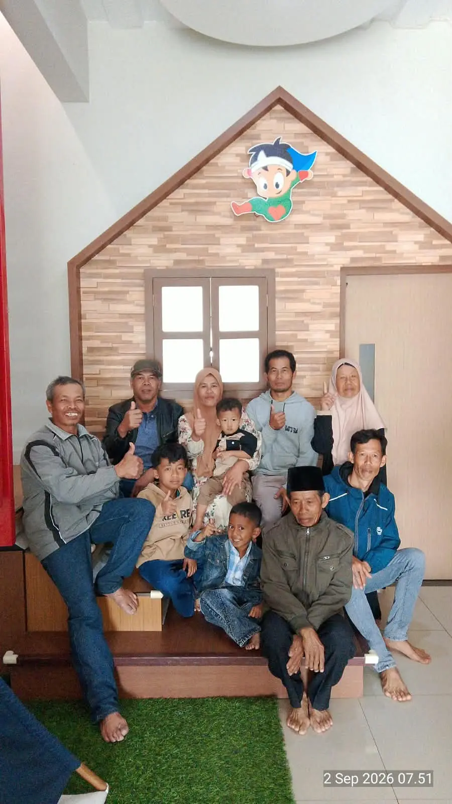 Keluarga besar berfoto bersama di spot foto estetik bentuk rumah